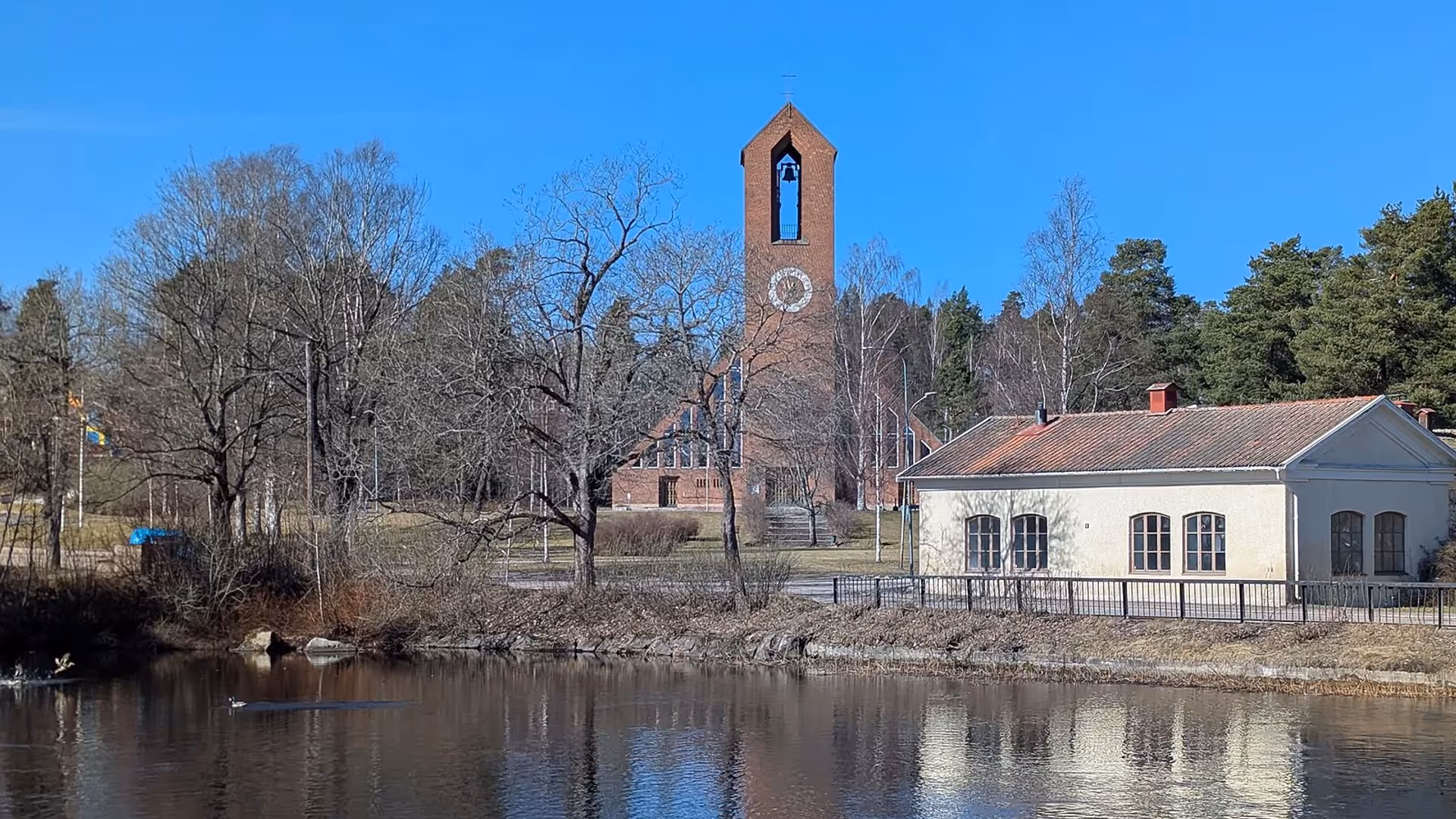 Hofors kyrka och klocktornet speglade i dammen en klar vårdag