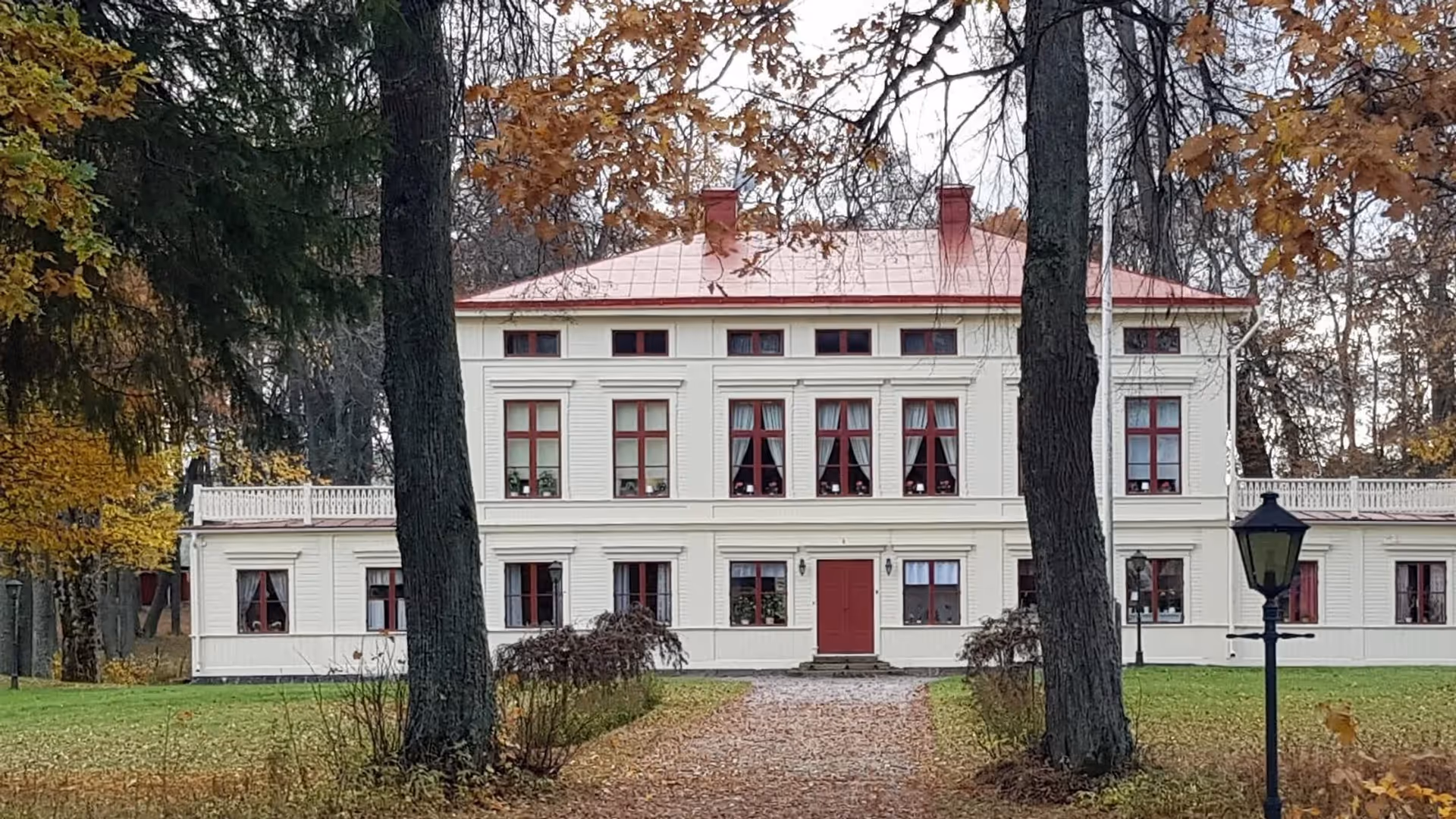 Åby gård i Valbo, en vit herrgård bland höstfärgade träd